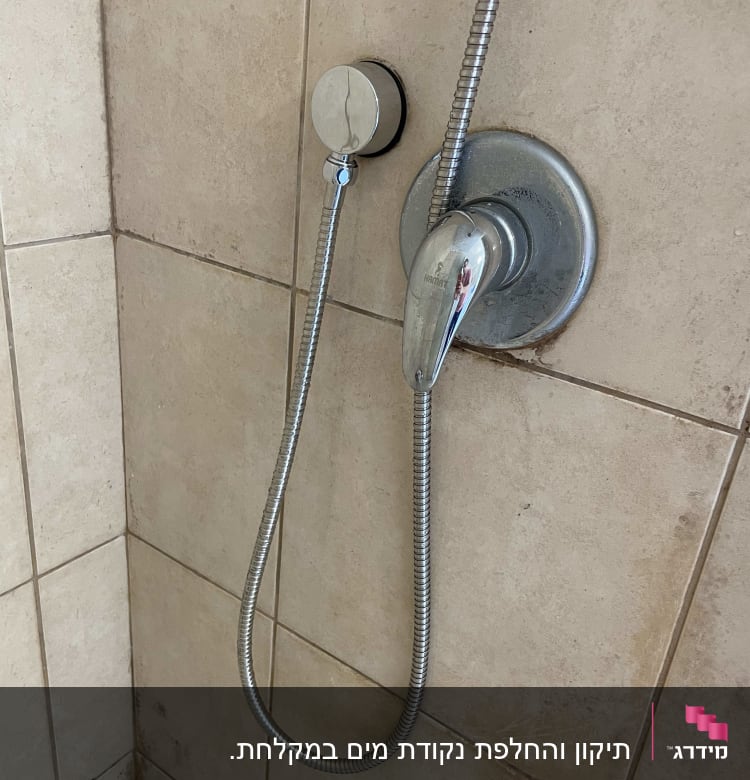 ברז מקלחת עם צינור מתכת על קיר אריחים